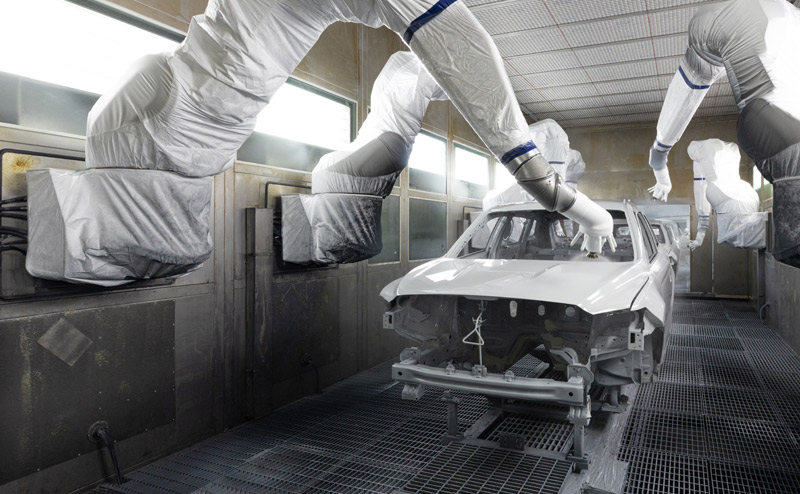 Robotic arms painting a car in an automotive body shop